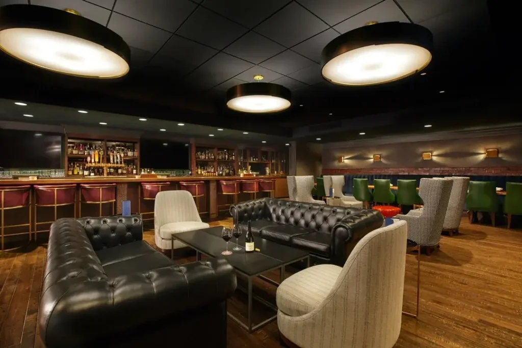 Four people dressed in stylish attire socializing and drinking at the bar inside Jockey Silks at the Galt House, a Louisville hotel.